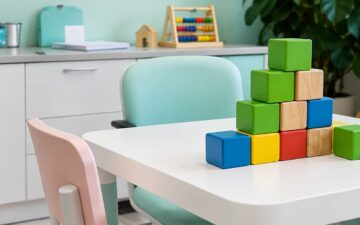Sala de atendimento infantil com mesa, cadeiras e blocos coloridos, representando um ambiente de aprendizagem e intervenção comportamental.
