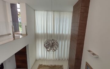 Cortina translúcida em sala com pé-direito duplo: a automação permite controlar a entrada de luz com um comando.